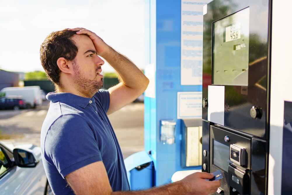 A man in Perth looking tense while checking fuel prices at a petrol station